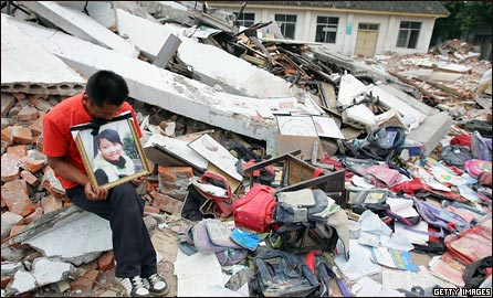 A grieving father sits in the rubble of a collapsed school in Mianzhu, Sichuan province