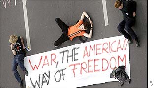 Protesters with anti-US banner lie on the road in Berlin