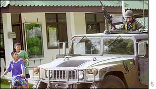 Children watch a Thai soldier in a military vehicle on patrol in Ratchaburi province 