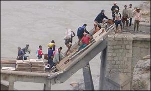 People crossing damaged bridge