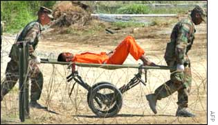 A prisoner is carried on a stretcher by two US soldiers at Guantanamo Bay