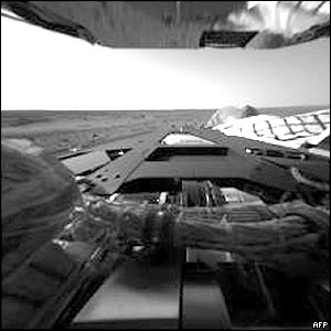 The first pictures, taken by the hazard avoidance camera on the Rover Spirit, show the rover's rear lander petal and, in the background, the Martian horizon.