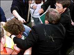 Back of Prescott with egg splattered on jacekt and left arm around  protester