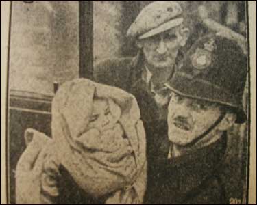 A policeman carries a young child to safety.