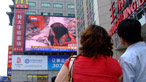 People looking at a giant TV screen.