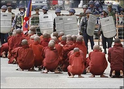 Các nhà sư đang cầu nguyện trong lúc công an canh chừng. Hình do báo Mandalay Gazette cung cấp