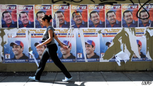 Mulher passa em frente a propaganda eleitoral de Hugo Chávez e Henrique Capriles (Foto: AFP/Getty Images)