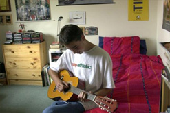 Image: Teenager playing guitar in his bedroom