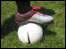 foot resting on football on grass