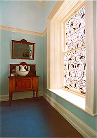 An upstairs corridor lit by natural light from a stained glass window. Natural available daylight is used ingeniously throughout the entire house