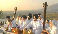 A group of men and women sit outside playing instruments
