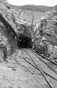 A view of the Dunnywater tunnel entrance. The railway tracks were for locomotive skips to bring out rubble. The pipelines carried unwanted water out of the tunnel and delivered high-pressure air to drive the drills at the workface. The large pipe sucked stale air from the tunnel.