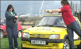 Michelle Andrews spraying champagne over a rally car.