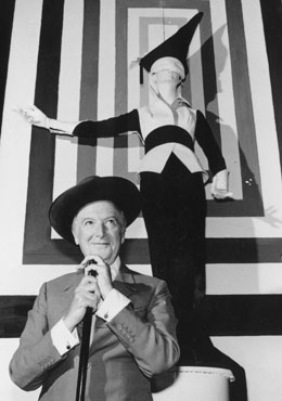 Cecil Beaton standing in front of an Ascot costume for My Fair Lady (1963) at his exhibition Fashion: An Anthology at the V and A , 1971. Photo by Keystone/Getty